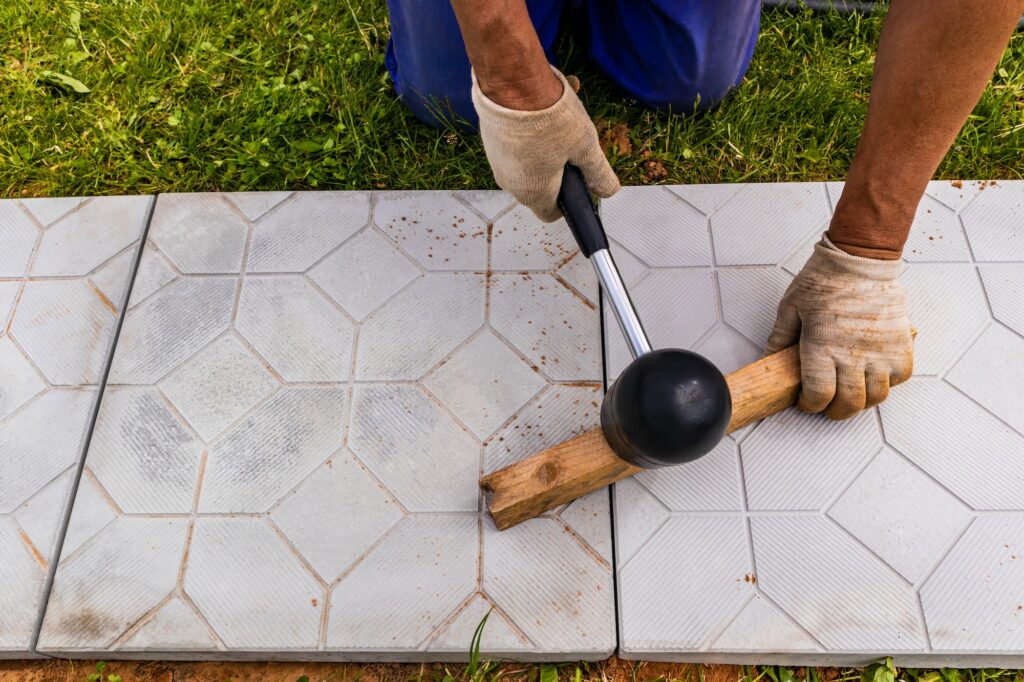 The master lays paving stones in layers. Garden brick pathway paving. Laying concrete paving slabs